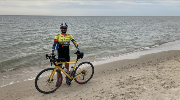 A picture of Yevhen holding his bicycle on a beach